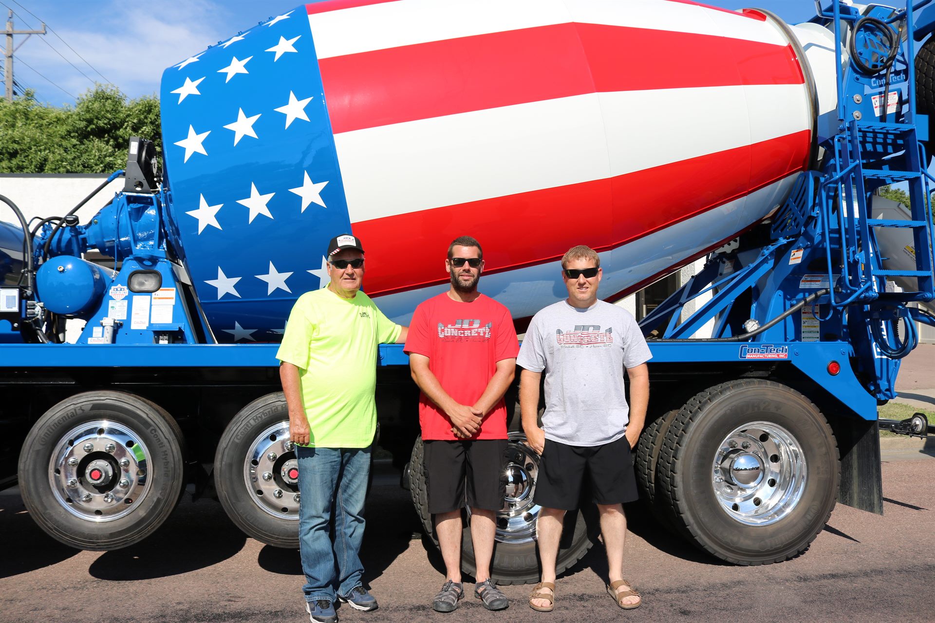 Three generations of the JD Concrete crew in front of the flag mixer truck