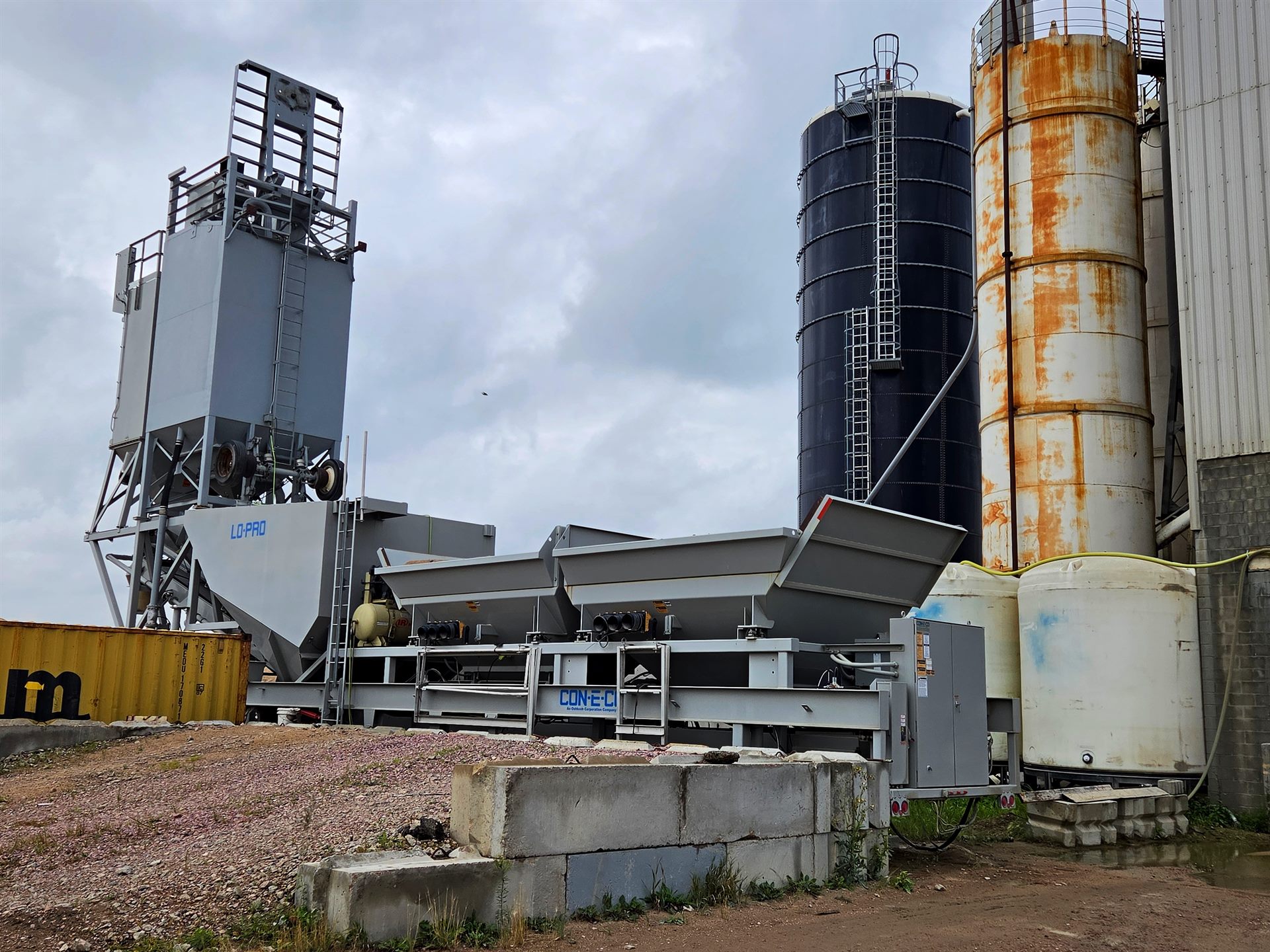A JD Concrete portable batch plant beside the silos